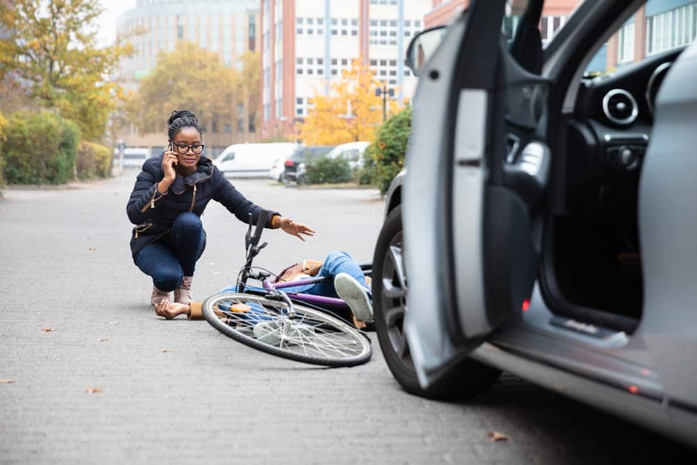 Image is of a person calling for help beside an injured cyclist, concept of an accident while biking in Aiken.