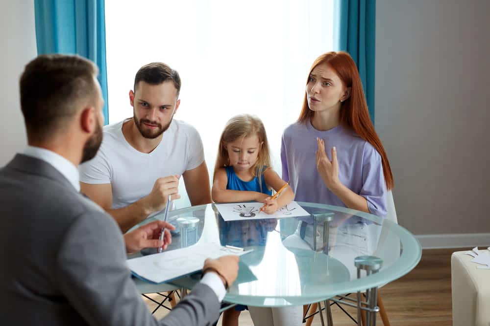 Image is of parents and their daughter meeting with a legal professional, illustrating discussions about parenting responsibilities under joint custody.