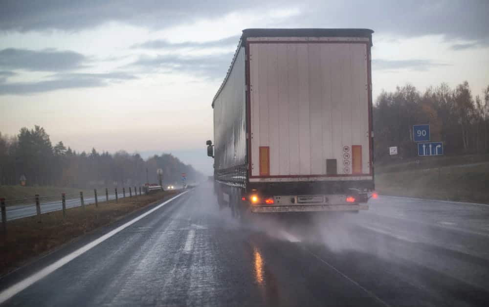 Image shows a large commercial truck traveling on a rain-soaked highway with reduced visibility, illustrating weather-related truck accidents in Aiken.