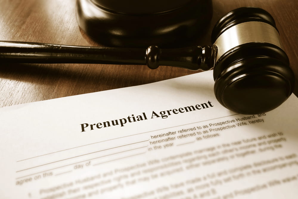 Image is of a judge's gavel resting on a prenuptial agreement document, concept of legal provisions and protections under an Aiken prenuptial agreement.