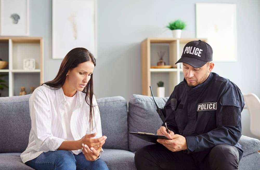 Image is of a police officer speaking with a woman at home, concept of a domestic violence in Aiken investigation.