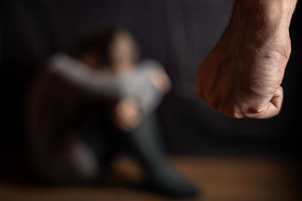 Image is of a clenched fist near a frightened person, concept of threats involving domestic violence in Aiken.